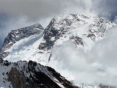 35 Broad Peak Central And Main Summits From Baltoro Glacier Between Goro II and Concordia Broad Peak (8047m) came into view before reaching Concordia. The Central Summit is on the left and the Main summit is on the far right. Its name was originally set as K3, right after the famed K2. But when Sir Martin Conway saw the peak in close detail, with its summit over a mile long, he named it Broad Peak which has stuck to this day. The first ascent of Broad Peak was completed by Marcus Schmuck, Fritz Wintersteller, Kurt Diemberger, and Hermann Buhl on June 9, 1957. This extremely small expedition marked a major step forward in the development of Himalayan climbing. Diemberger: [Buhl's] plan was that from base camp onwards there would only be climbers on the mountain; they would do everything, load-carrying, establishment of camps and, finally, the assault on the summit. And it was all to be done without the use of oxygen. Diemberger reached the summit just as Marcus Schmuck and Fritz Wintersteller started their descent. As Diemberger was descending from the summit he met Buhl still ascending. Slowly, with all that incredible strength of his will, he started to move, very slowly, upwards. ... Two men were standing on a peak, still breathing heavily from the ascent, their limbs weary - but they did not notice it; for the all-enveloping glory of the sun's low light had encompassed them too. Deeper and deeper grew the colours. ... No dream-picture, this. It was real enough, and it happened on the 26,404-foot summit of Broad Peak.  Summits And Secrets by Kurt Diemberger.